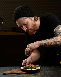 Le chef cuisinier de Pub G6 assaisonne un plat de saumon de l'Atlantique servie en sauce à la bière