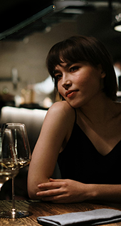 Une jeune femme assise avec un verre de vin au Pub G6