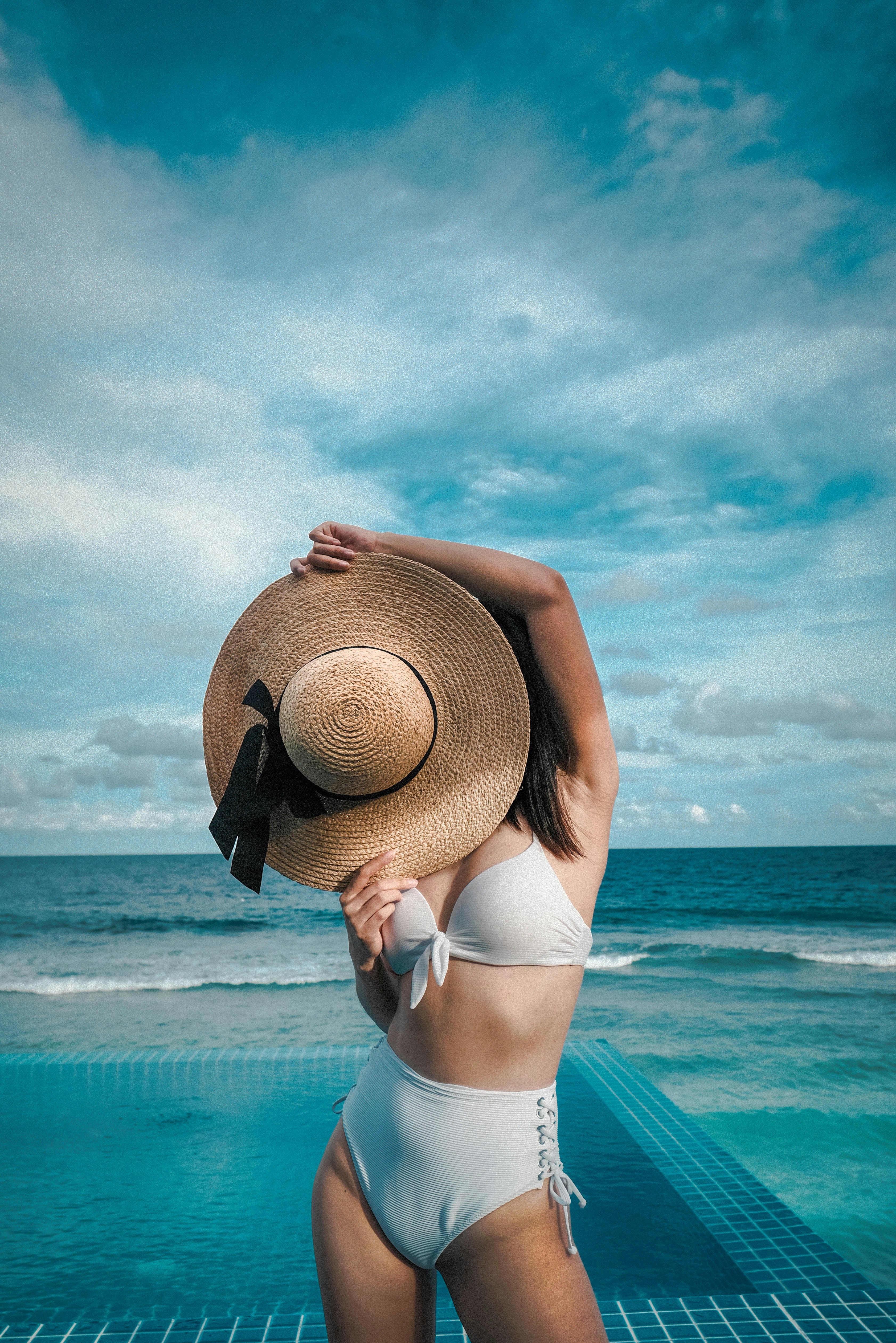 Femme sur la plage avec un chapeau devant son visage